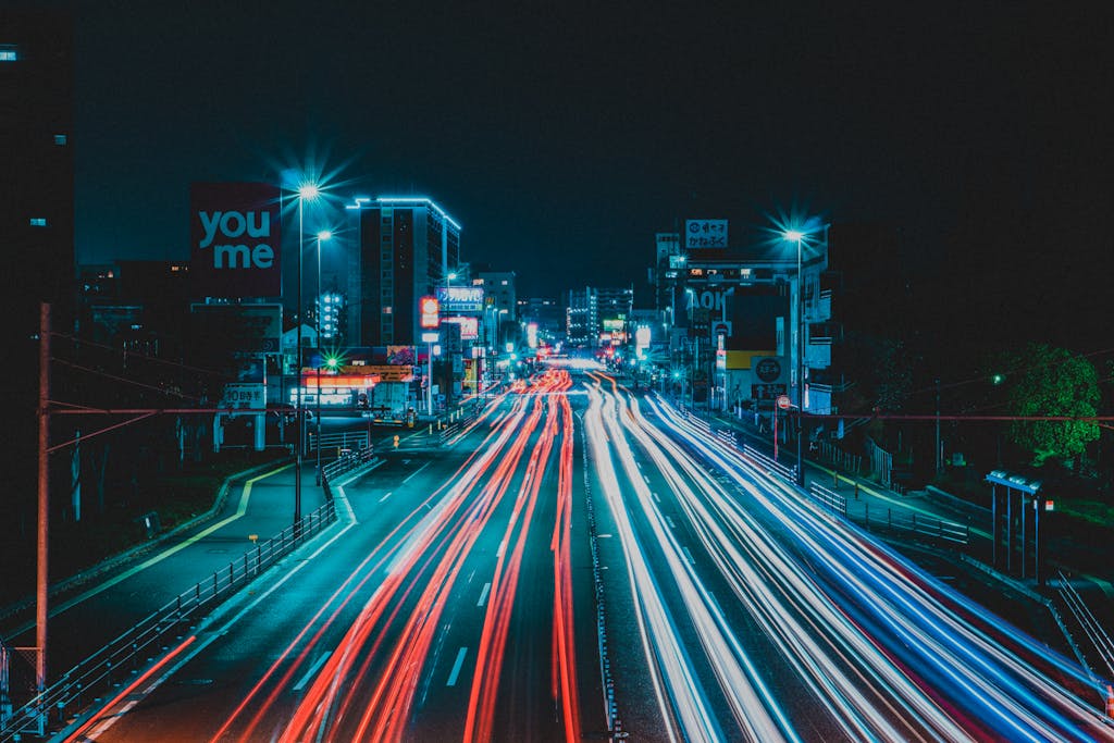 Dynamic long exposure shot of a city road at night with colorful light trails.