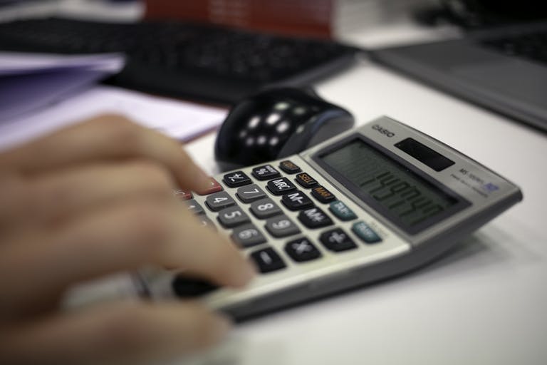 Close-up of a hand using a calculator on an office desk for accurate calculations.