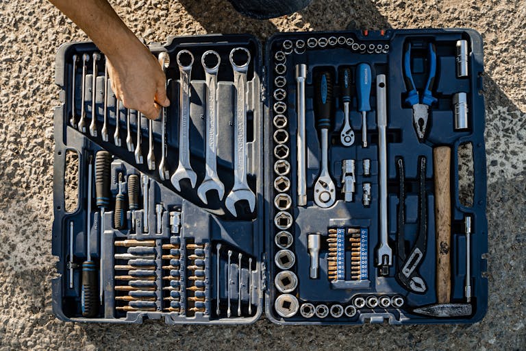 Open toolkit with assorted hand tools, including wrenches and pliers, captured outdoors.